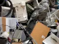 Stary sprzęt AGD, w tym odkurzacz i drukarka, tworzą stos. Zastanawiasz się, gdzie wyrzucić żelazko? To miejsce to idealny przykład elektrośmieci.