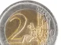 Gros plan d'une pièce de 2 euros commémorative. Le chiffre "2" est bien visible, ainsi que le mot "EURO" et une carte de l'Europe.