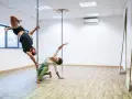 Para ćwiczy pole dance, pokazując efekty odchudzania. On wisi na rurze, ona kuca obok.