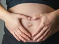 Dłonie tworzą serce na brzuchu, symbolizując miłość i troskę o to, jak dziecko oddycha w brzuchu.