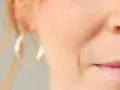 Nahaufnahme eines Gesichts mit sichtbarer Nasolabialfalte, die mit 40 Jahren typisch ist. Eine Frau mit dezentem Lächeln.