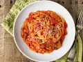 Spaghetti al pomodoro con pezzi di carne e cipolla, uno dei classici sughi per pasta, spolverati di parmigiano.