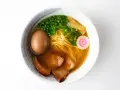 A miseczce shoyu ramen z makaronem, jajkiem, plastrami wieprzowiny, szczypiorkiem, bambusem i różową rybną kluską.