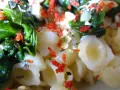 Pyszny makaron ze szpinakiem i serem pleśniowym, posypany czerwonymi płatkami chili i ziołami.