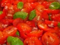 Frischer Tomatensalat mit Zwiebeln und Basilikum, bereit für ein leichtes Tomatensalat Dressing.