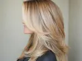 Kobieta z pięknymi, warstwowymi włosami w odcieniu ombre blond.