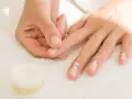 Application de crème pour hydrater la peau sèche autour des ongles.