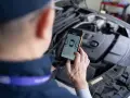 Mechanik sprawdza kody błędów DTC Renault na telefonie, analizując raport z pomiaru lakieru.