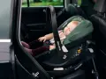 Schlafendes Baby in einer grünen Babyschale mit Isofix-Autobefestigung. Sicher und bequem auf Reisen.