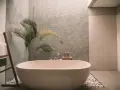 Ett modernt badrum med fristående badkar, en grå texturerad vägg och en palm. Perfekt för att renovera badrum och skapa en spa-känsla.