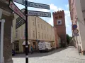 Ulica z wieżą i drogowskazami do Sądu Rejonowego, Krzywej Wieży i Zamku. Odkryj mało znane miejsca na Dolnym Śląsku.