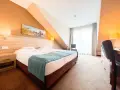 Przytulny pokój hotelowy z wygodnym łóżkiem, biurkiem i oknem. Idealne miejsce na nocleg tranzytowy, by odpocząć w podróży.