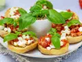 Bruschetta z pomidorami i mozzarellą – pyszny przepis na letnią przekąskę. Chrupiące grzanki z dodatkiem świeżej bazylii.
