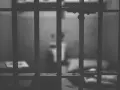 Widok przez kraty więzienne. W tle niewyraźna postać, symbolizująca nadzieję na wcześniejsze zatarcie skazania i nowe życie.