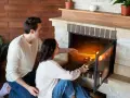 Pareja añade leña a la chimenea, creando un ambiente acogedor. Los insertables de madera se queman, iluminando la habitación.