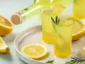 Orzeźwiający limoncello co to? Włoski likier cytrynowy w kieliszkach, ozdobiony cytryną i rozmarynem, obok butelki i świeżych cytryn.