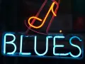 Néon bleu lumineux "BLUES" avec une note de musique rouge orangé au-dessus. L'ambiance parfaite pour une soirée blues.