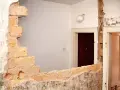 Rozbiórka budynku, odsłonięta wspólna ściana z cegieł między drzwiami.