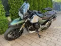 Zielony motocykl Moto Guzzi V85TT z silnikiem V, gotowy na przygodę.