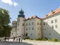 Zamek w Pieskowej Skale z charakterystyczną wieżą zegarową i renesansową attyką. Zwiedzający spacerują po dziedzińcu.