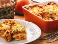 Zapiekanka makaronowa z mięsem mielonym w sosie śmietanowym, podana na talerzu i w naczyniu żaroodpornym.