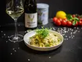Aksamitne risotto z kurczakiem i szparagami, udekorowane kiełkami. Obok kieliszek białego wina i butelka.