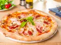 Pizza garnie de jambon, tomates séchées et champignons, parfaite pour une recette pâte à pizza rapide. Une salade fraîche est servie à côté.