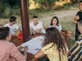 Un groupe discute autour d'une table en bois lors d'une sortie team building en plein air.