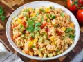 Bunter Couscous-Salat mit Tomaten, Paprika und frischer Petersilie, garniert mit einem Petersilienblatt.