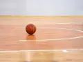 Balón de baloncesto sobre los pavimentos deportivos de madera pulida, listo para el juego.