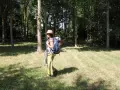 Une randonneuse avec un sac à dos et une poche à eau visible. Elle est dans une forêt, prête pour son aventure.