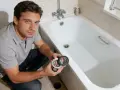 Man holding bathtub drain parts, demonstrating how to install a bathtub.