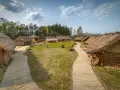 Drewniana osada średniowieczna Sławutowo z chatami krytymi strzechą, kamieniami i ścieżkami.
