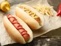 Dwa hot dogi, jeden z keczupem, drugi z musztardą, obok frytek. Zastanawiasz się, ile kalorii ma hot dog?