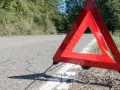 Czerwony trójkąt ostrzegawczy odległości stoi na poboczu drogi, sygnalizując awarię.
