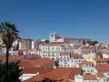 Słoneczna Portugalia, pogoda w lutym zachwyca. Widok na Lizbonę z palmą i kościołami na wzgórzach.