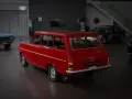 Röd veteranbil med ålder, en Opel Caravan, står i en bilhall bredvid en blå bil och en tävlingsbil.