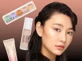 Une femme au teint lumineux, prête pour le maquillage, avec une palette de correcteurs, un fond de teint sérum et un highlighter Astra.