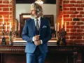 Elegancki mężczyzna w niebieskim garniturze w kratę, z wzorzystą poszetką i krawatem. Pokazuje, jak dobrać koszulę do garnituru.