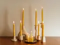Velas amarillas de abeja en candelabros de cerámica. Una vela de palo santo para que sirve, ilumina el espacio con su suave resplandor.