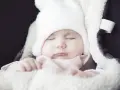 Słodki maluch w białej czapce śpi, jego **sine usta** lekko uchylone. Otulony w miękki kocyk, wygląda jak mały aniołek.