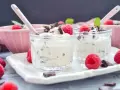 Zwei Gläschen mit cremigem Dessert, garniert mit Himbeeren und Schokostückchen. Ein köstliches Herrencreme Rezept zum Genießen.