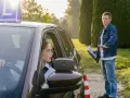 Młoda kobieta w okularach za kierownicą samochodu z literą "L", instruktor obok. Czy kurs na prawo jazdy przepada?