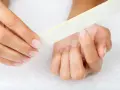 Une main lime délicatement ses ongles, comme un remède de grand-mère pour un ongle abîmé.