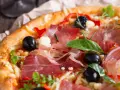 Pyszna pizza z cienko pokrojoną, aromatyczną szynką, czarnymi oliwkami i papryką. Idealna na każdą okazję!
