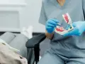 Dentysta pokazuje na modelu, jak radzić sobie z bólem, gdy rosnący ząb mądrości sprawia kłopoty.