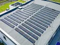 Duży dach płaski pokryty panelami fotowoltaicznymi, które zbierają energię słoneczną.