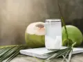 Un verre d'eau de coco, riche en potassium, à côté de noix de coco fraîches et de feuilles de palmier.