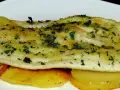 Delicioso lenguado al horno con patatas doradas y hierbas frescas.