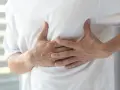Mann hält sich die Brust, als ob eine rippe eingeklemmt wäre.